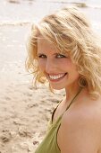 Portrait of beautiful blonde woman wearing green halter top, smiling