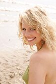 Portrait of beautiful blonde woman wearing green halter top, smiling