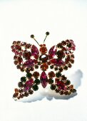Close-up of red butterfly shaped brooch on white background