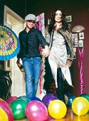 Cheerful couple celebrating at a party with champagne, surrounded with colourful balloons