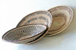 Close-up of three shallow bowls made of steppe grass with ornament design in ethnic style
