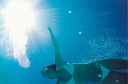 Unterwasser-Foto: brünette Frau im Bikini in Weiß beim Schwimmen, blau