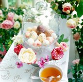 Pralines and dome shaped glass container with flowers on table