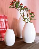 3 weiße Keramikvasen auf einer Borte 1 Zweig mit roten Beeren