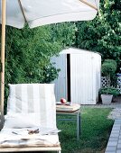 Close-up of lounger under a parasol against garden shed