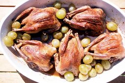 Baked pigeons with grapes in baking dish