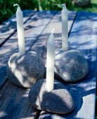 Kerzenhalter aus drei großen Steinen , weiße Kerzen darin