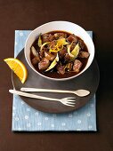 Lamb stew with figs in a bowl with brown plate, fork and spoon