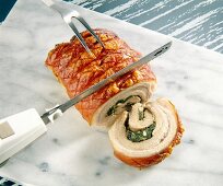Close-up of electric knife cutting roast meat roll into slices