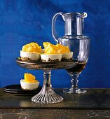 Mini lemon cheesecakes on a cake stand against a blue background