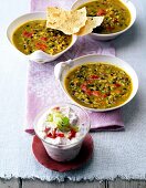 Three kinds of Indian styled lentil soup in white serving bowl along with yogurt dip
