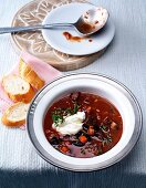 Goulash soup with black beans and bread slices in bowl