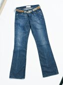 Close-up of blue jeans with belt on white background