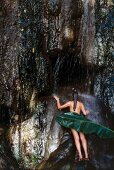 Frau steht nackt und naß unter tropischem Wasserfall