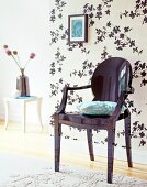 Black plastic chair in front of floral patterned wallpaper