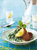 Lamb cutlets with yogurt and spinach salad on plate