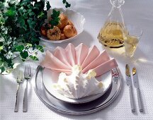 Pastel folded napkin with large shell and cutlery on plate