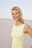 Portrait of pretty woman with windswept hair wearing yellow top standing and smiling