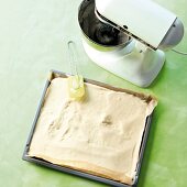 Lemon cream being spread in baking tray having butter paper in it