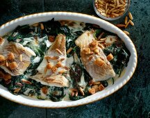 Close-up of saithe fillet with spinach and pine nuts in casserole