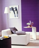 Wohnzimmer mit lilafarbenen Wänden weißem Sessel und Beistelltisch