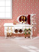 Close-up of golden and silver earrings arranged on table and chair in doll house