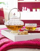Glass teapot and cup on white tray