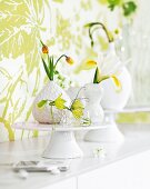 Drei Blumenvasen mit Blumen auf weißer Tortenplatte