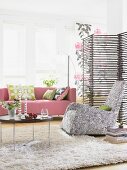 Living room in black and white with pink sofa and bamboo folding screen