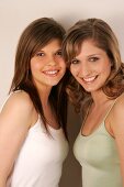 Portrait of two beautiful woman standing side by side, smiling
