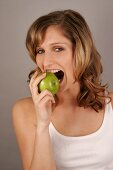 Portrait of young woman eating green apple