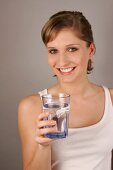 Woman wearing white top holding glass of water
