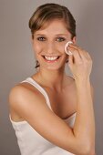 Portrait of beautiful blonde woman cleansing face with pad, smiling