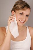 Portrait of gray eyed Charlotte woman with blonde hair cleaning her face, smiling