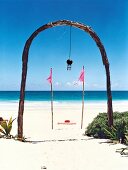 View of sea through arch with hanging wind chime on beach