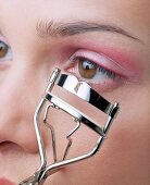 Close-up of woman curling her eyelashes with eyelash curler