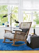 Rocking chair on blue fur carpet with lamp against window