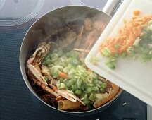 Vegetables being added to seafood in pan