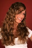 Beautiful woman with long curly hair wearing white top standing and laughing