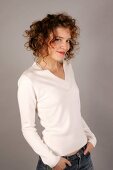 Portrait of beautiful woman with curly hair wearing white sweater, smiling widely