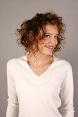 Portrait of beautiful woman with curly hair wearing white sweater, smiling widely