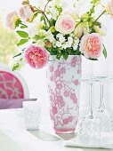 Rosenstrauß in Glasvase mit Blumenmuster auf einem Tisch