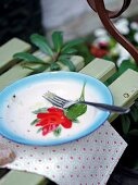 Blauer Teller mit roter Blüte und Re sten vom Essen, Gabel auf dem Tisch