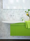 White basin with green cabinet against flowered wall