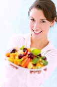 Portrait of beautiful woman holding plate of fresh fruits in hand