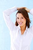 Portrait of pretty brunette woman wearing white blouse, smiling