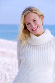Portrait of beautiful blonde woman wearing white sweater, smiling