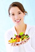 Portrait of beautiful woman holding plate of fresh fruits in hand