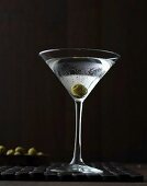 A Martini with an olive in a stemmed glass