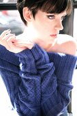 Pensive woman wearing blue sweater propped on elbows, looking away